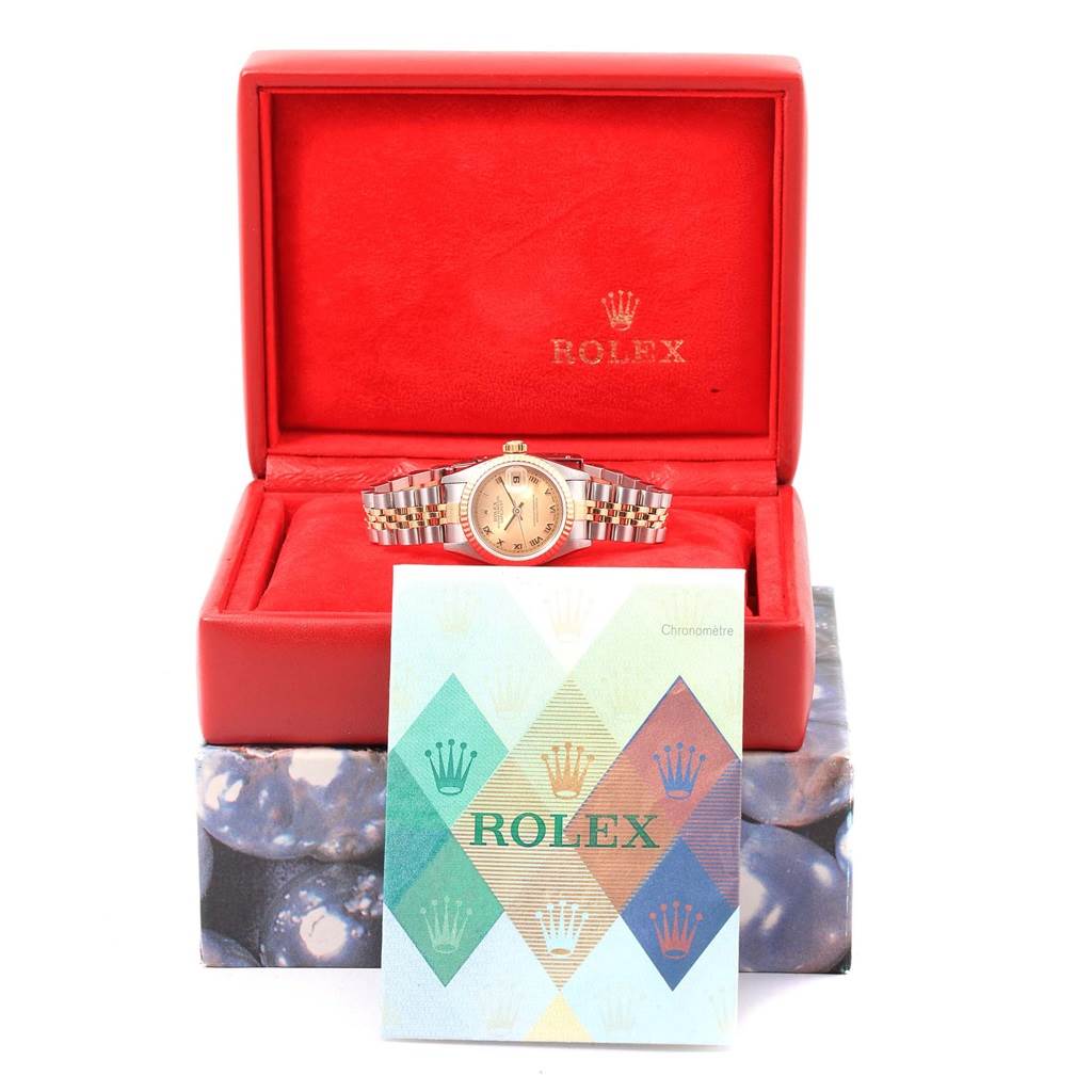 The Rolex Datejust 79173 Women's Steel and Gold (two tone) Champagne Dial 79173 Women's Steel and Gold (two tone) Champagne Dial watch is displayed front-on in an open red box with documentation in front.