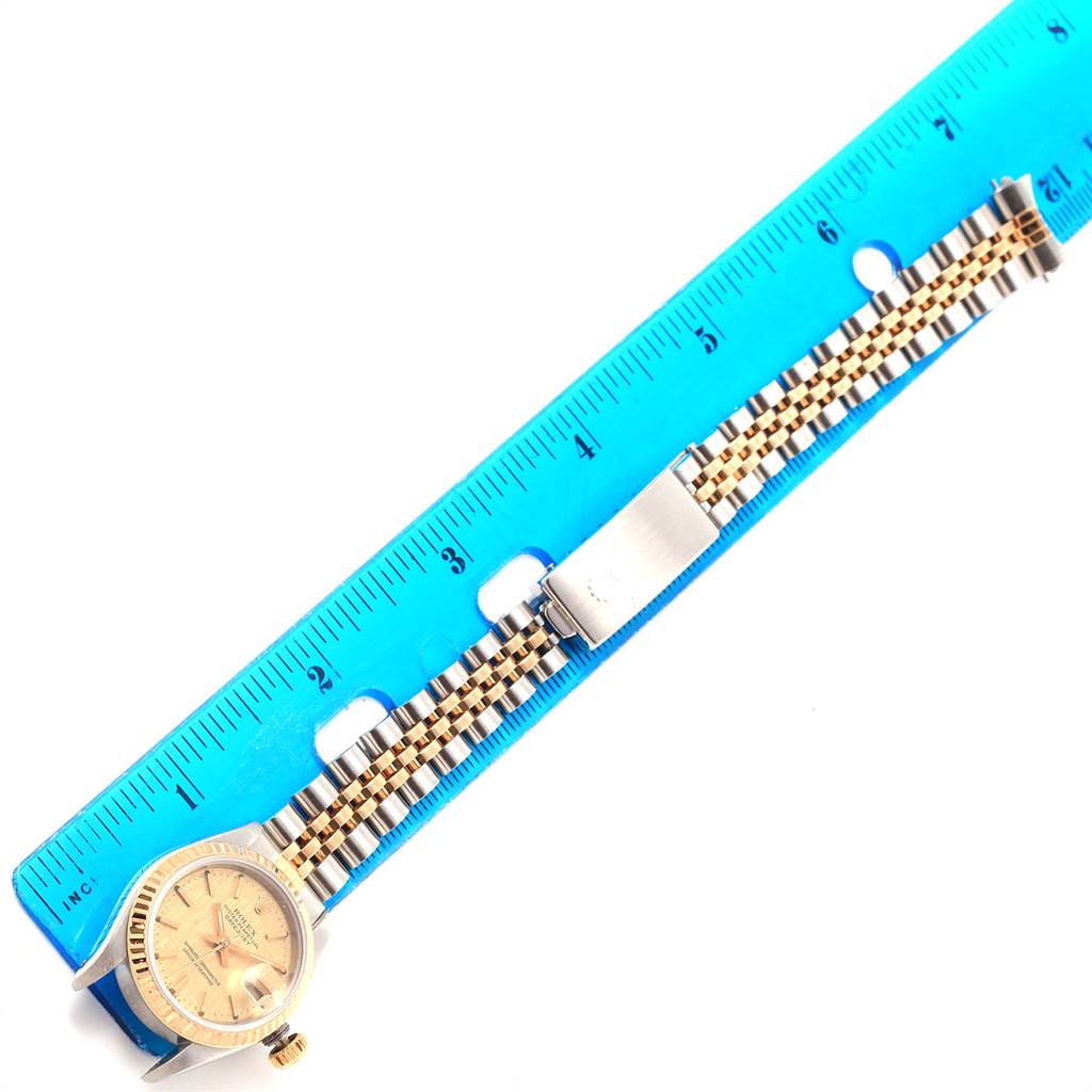 The Rolex Datejust 69173 Women's Stainless Steel Champagne Dial 69173 Women's Stainless Steel Champagne Dial watch is photographed from above, showcasing the face, case, bezel, and full bracelet against a blue ruler.