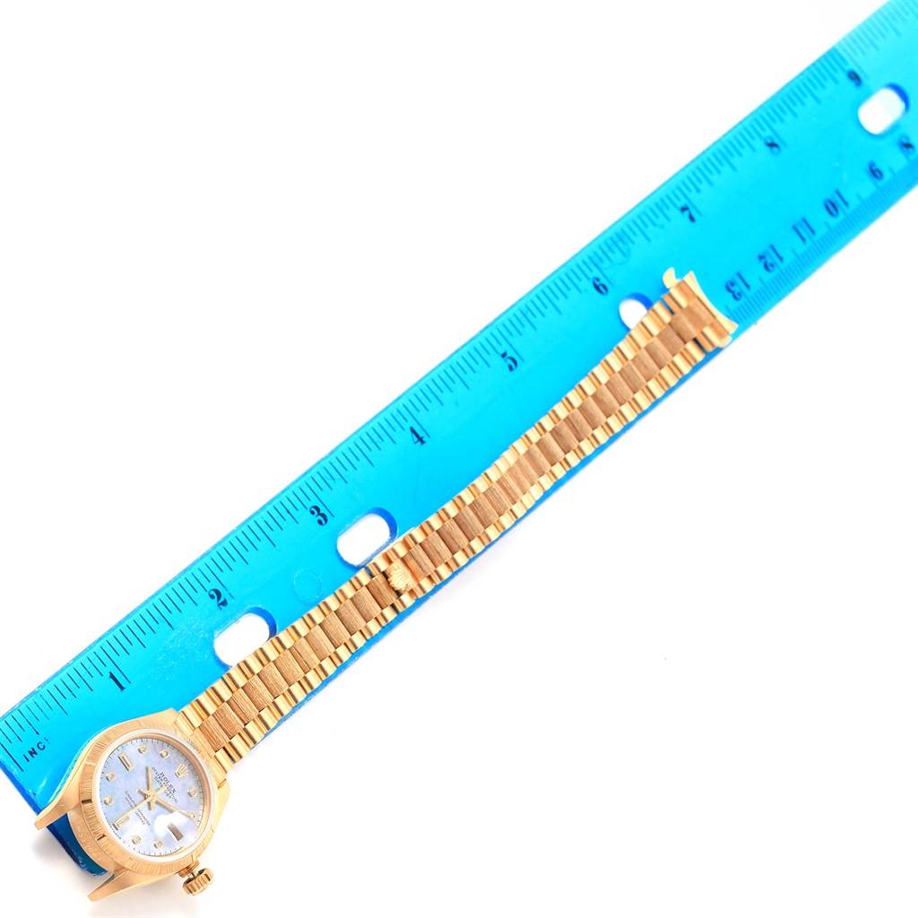 The image shows the full length of a Rolex Datejust 69278 Women's Yellow Gold Mother of Pearl Dial 69278 Women's Yellow Gold Mother of Pearl Dial watch next to a blue ruler for scale.