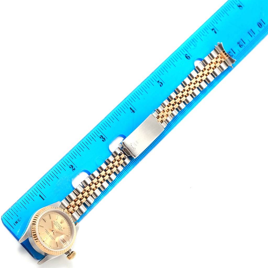 The image shows a side angle of a Rolex Datejust 69173 Women's Stainless Steel Champagne Dial 69173 Women's Stainless Steel Champagne Dial watch with a blue ruler placed next to its bracelet for scale.