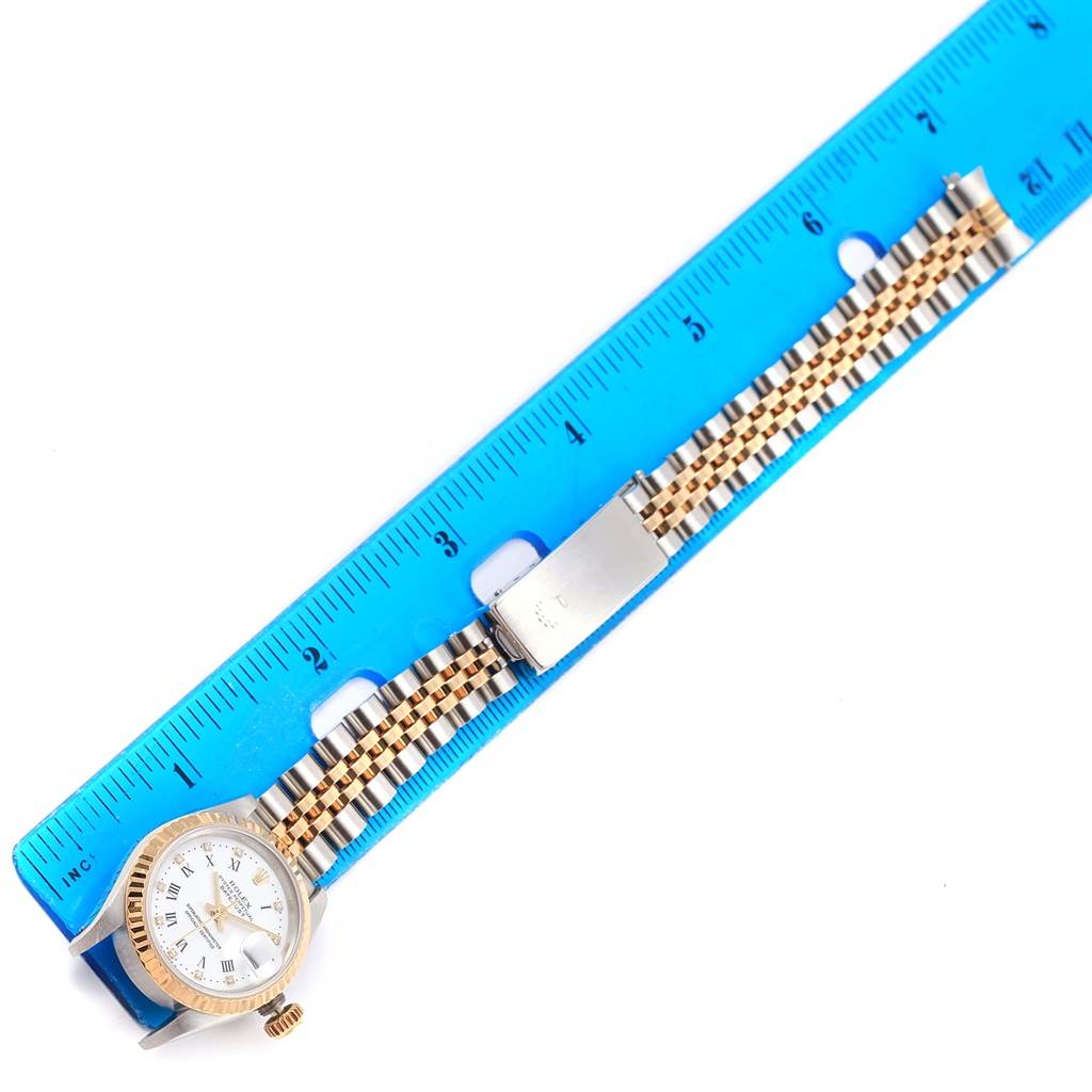 The image shows a horizontal view of a Rolex Datejust 69173 Women's Stainless Steel White Dial 69173 Women's Stainless Steel White Dial watch next to a ruler, focusing on the face and band.