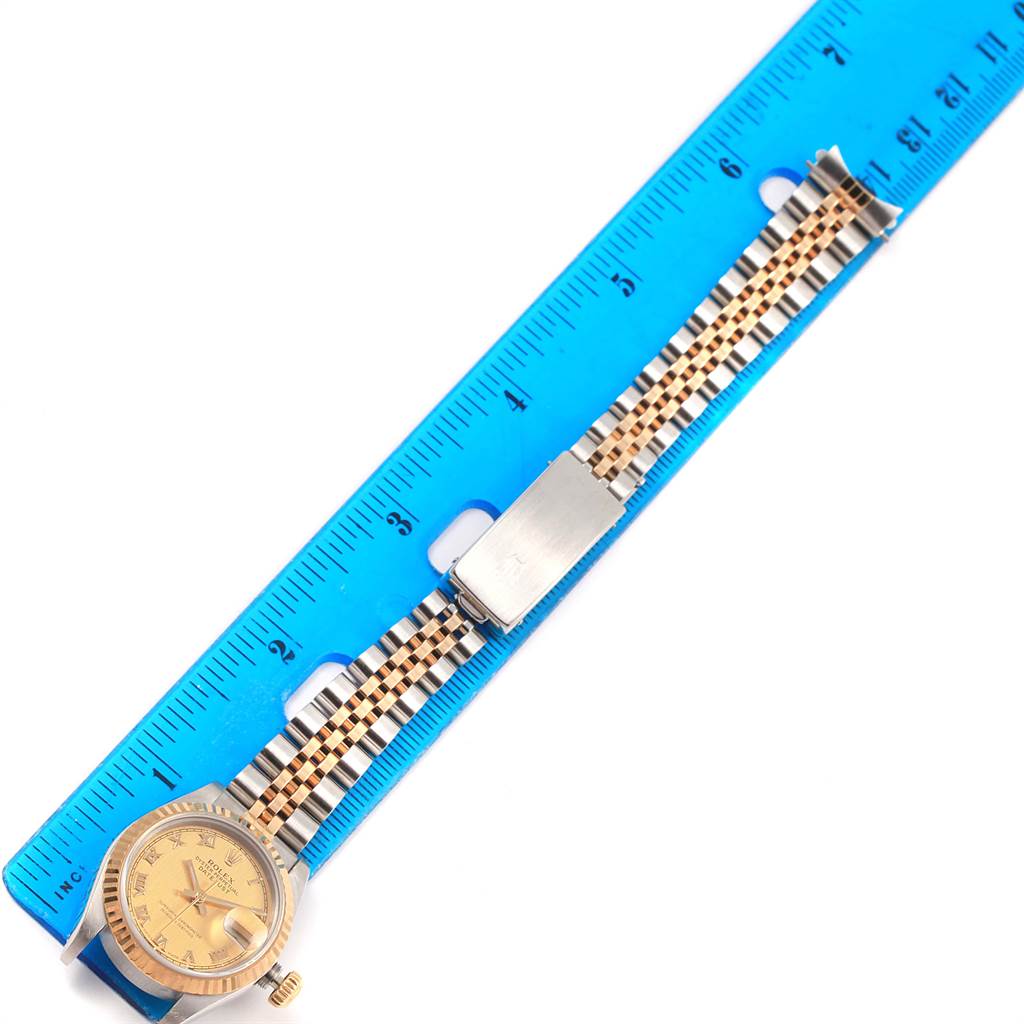 The Rolex Datejust 69173 Women's Stainless Steel Champagne Dial 69173 Women's Stainless Steel Champagne Dial watch is shown from a top-down angle, displaying the face, bracelet, and clasp beside a blue ruler.