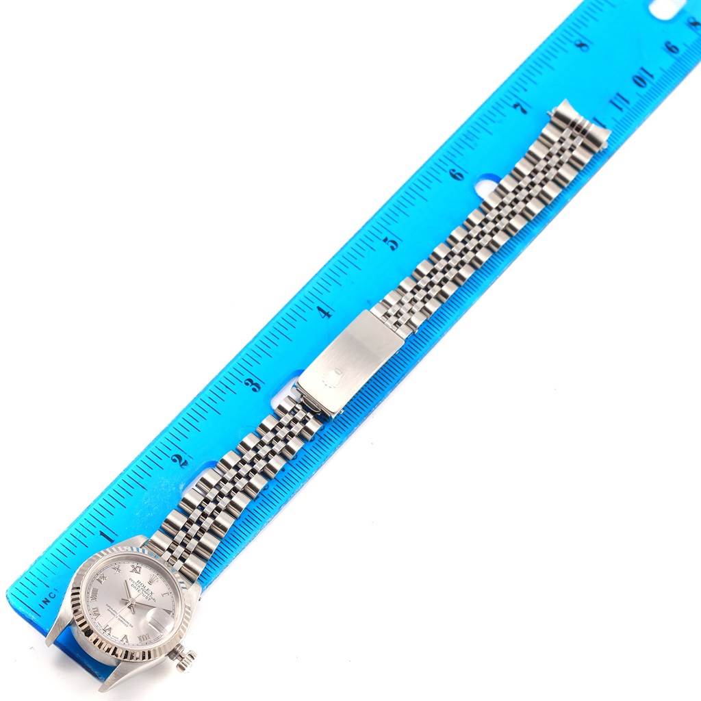 The Rolex Datejust 69174 Women's Stainless Steel Silver Dial 69174 Women's Stainless Steel Silver Dial watch is shown lying flat with its entire face, bracelet, and clasp displayed next to a blue ruler.