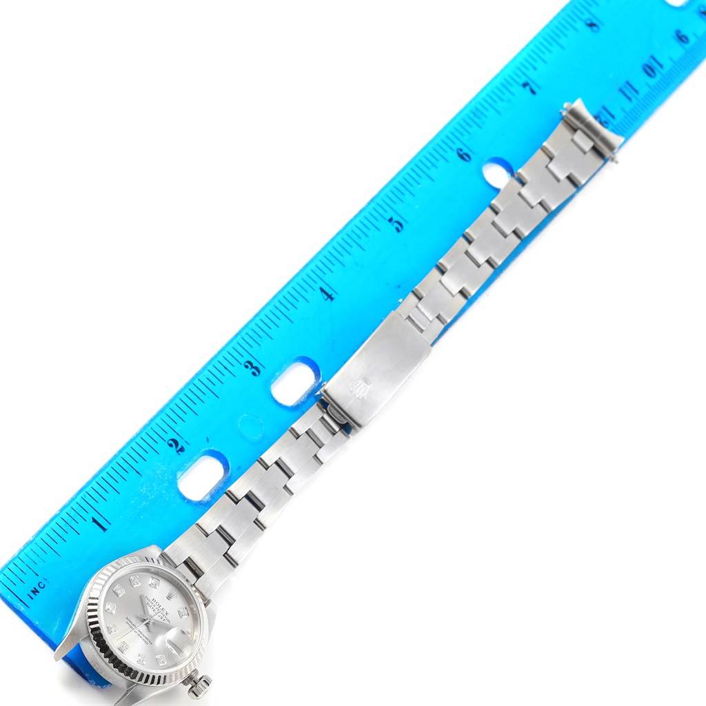 The image shows a top-down view of a Rolex Datejust 79174 Women's Stainless Steel Silver Dial 79174 Women's Stainless Steel Silver Dial watch with its band fully extended next to a blue ruler.