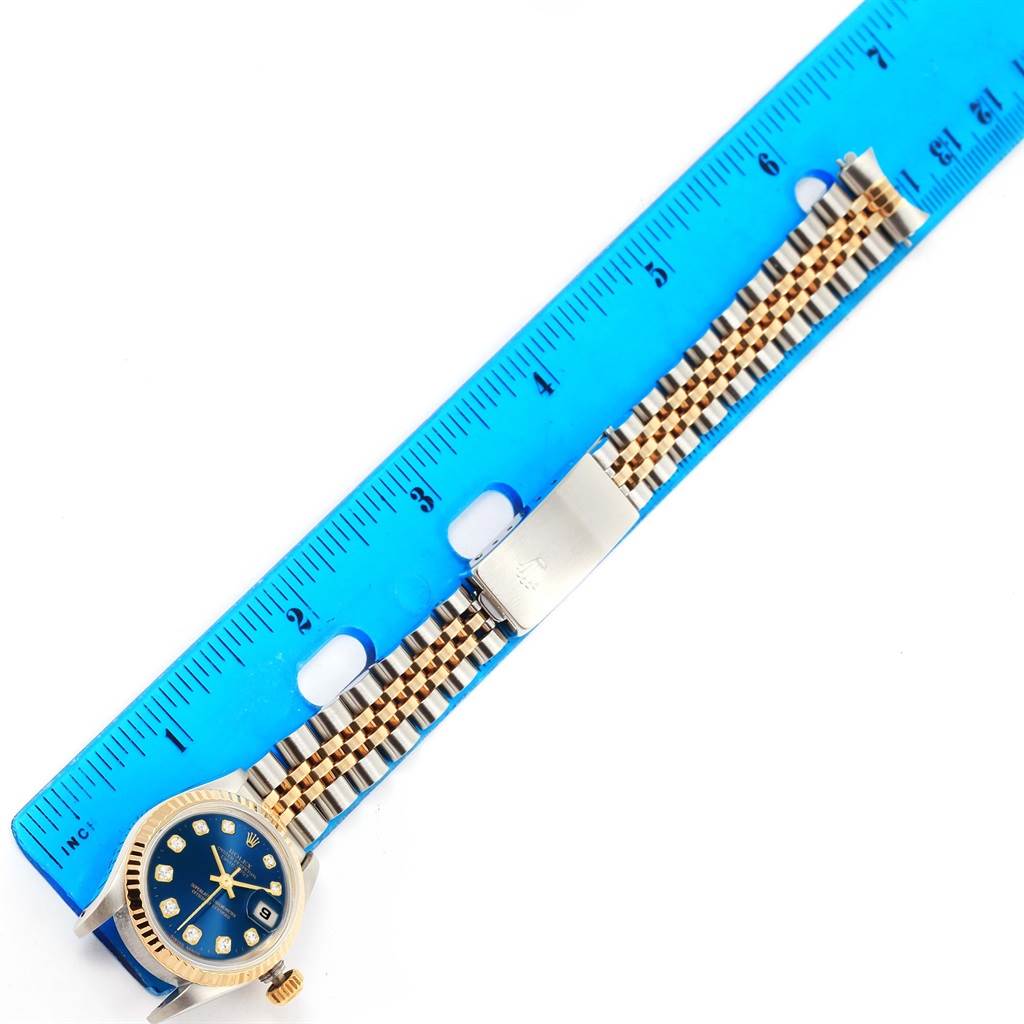 The image shows a top view of a Rolex Datejust 69173 Women's Steel and Gold (two tone) Blue Dial 69173 Women's Steel and Gold (two tone) Blue Dial watch, highlighting its dial, bezel, and two-tone bracelet next to a blue ruler.