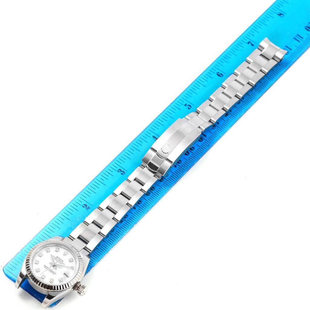 The Rolex Datejust 179174 Women's Stainless Steel White Dial 179174 Women's Stainless Steel White Dial watch is shown from an overhead view, displaying the face, case, and full bracelet against a ruler for scale.