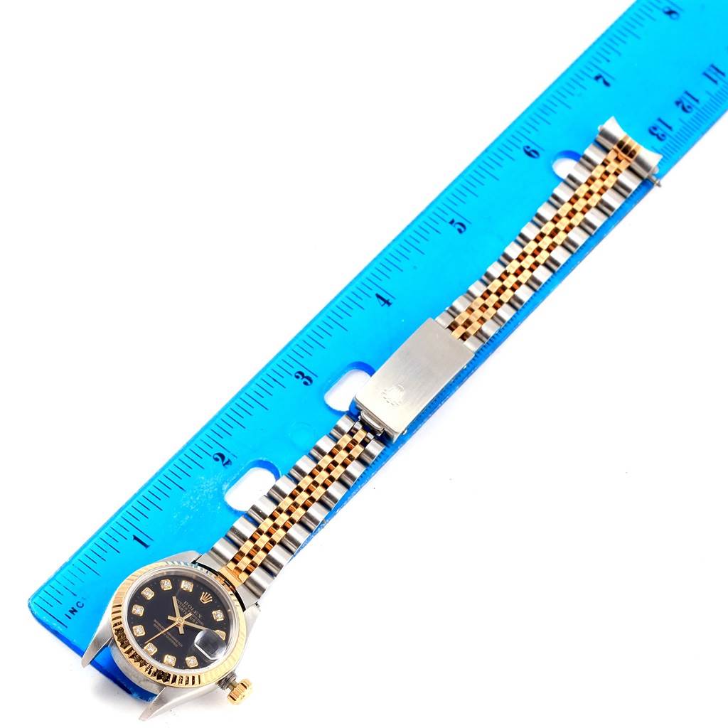 The image shows a Rolex Datejust 69173 Women's Stainless Steel Black Dial 69173 Women's Stainless Steel Black Dial watch placed beside a ruler, highlighting the watch's gold and silver bracelet and its black dial.