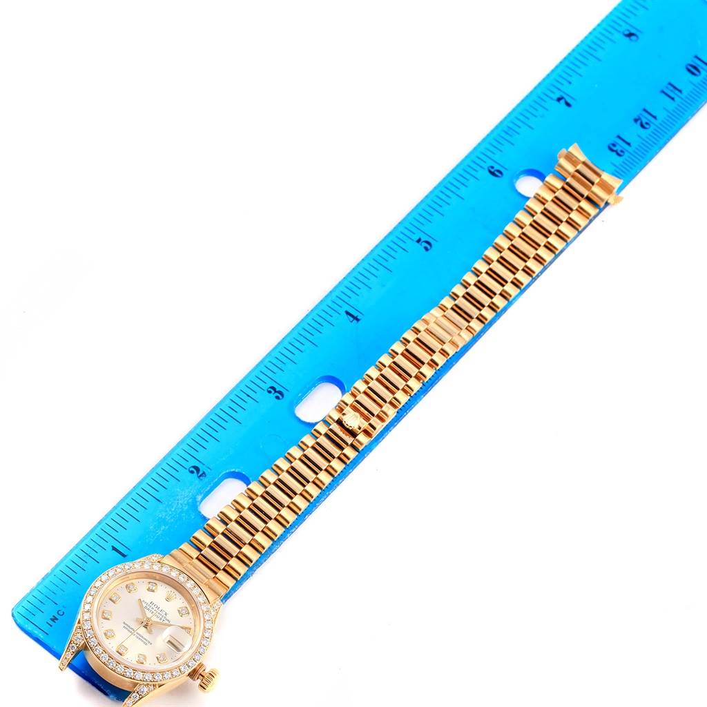 The Rolex Datejust 69238 Women's Yellow Gold Silver Dial 69238 Women's Yellow Gold Silver Dial watch is shown from a top-down angle next to a ruler, displaying its face and full bracelet.