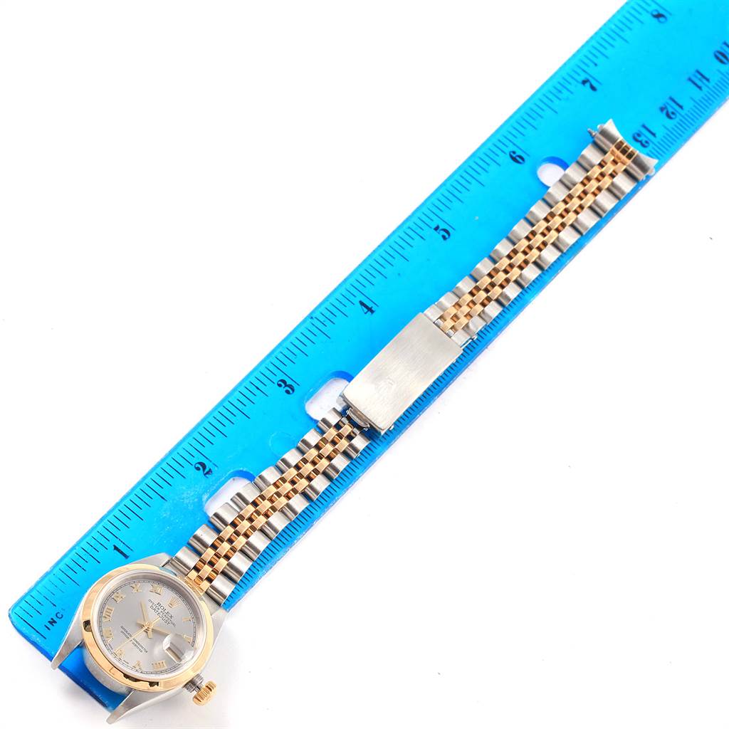 This image shows a top-view angle of a Rolex Datejust 79163 Women
s Steel and Gold (two tone) Grey Dial 79163 Women
s Steel and Gold (two tone) Grey Dial watch with its two-tone bracelet and clasp, alongside a blue ruler for measurement.