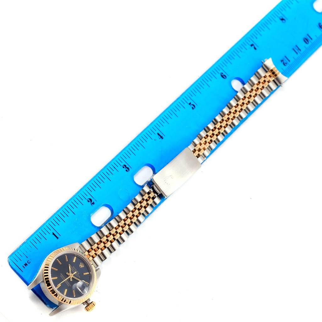 The Rolex Datejust 69173 Women's Stainless Steel Blue Dial 69173 Women's Stainless Steel Blue Dial watch is shown from a top-down angle alongside a blue ruler, highlighting its face, band, and clasp.