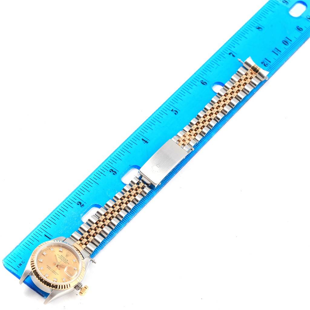 This image shows a Rolex Datejust 69173 Women's Stainless Steel Champagne Dial 69173 Women's Stainless Steel Champagne Dial watch lying flat next to a ruler, revealing its face, bezel, and jubilee bracelet.