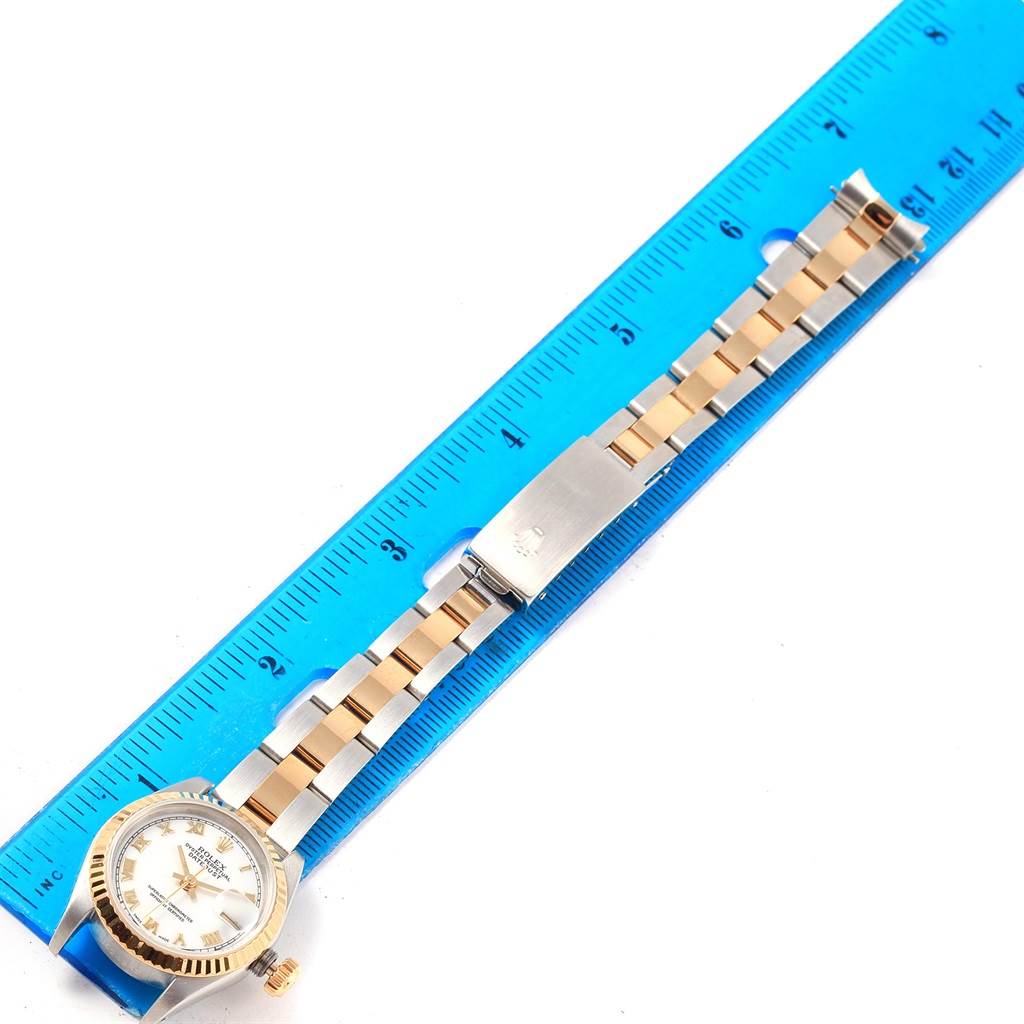 This image shows a Rolex Datejust 69173 Women
s Stainless Steel White Dial 69173 Women
s Stainless Steel White Dial watch laid flat next to a blue ruler, displaying its face and part of the bracelet.