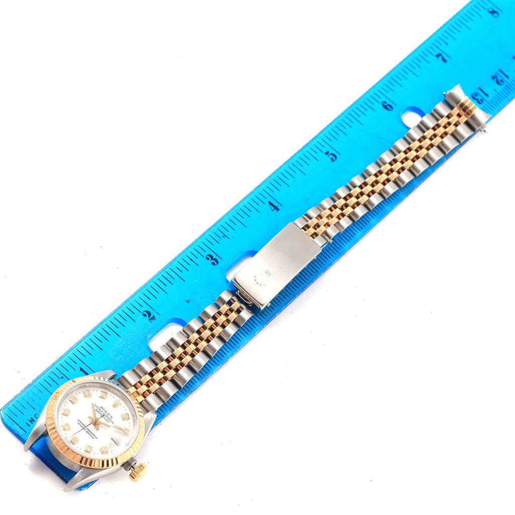 The image shows a Rolex Datejust 69173 Women's Stainless Steel White Dial 69173 Women's Stainless Steel White Dial watch placed next to a blue ruler, displaying the watch face, bezel, band, and clasp.