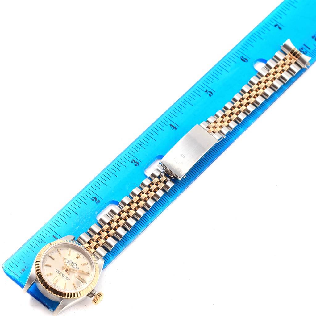 The image shows a top view of a Rolex Datejust 69173 Women's Stainless Steel Silver Dial 69173 Women's Stainless Steel Silver Dial watch against a blue ruler, highlighting its face, bracelet, and clasp.