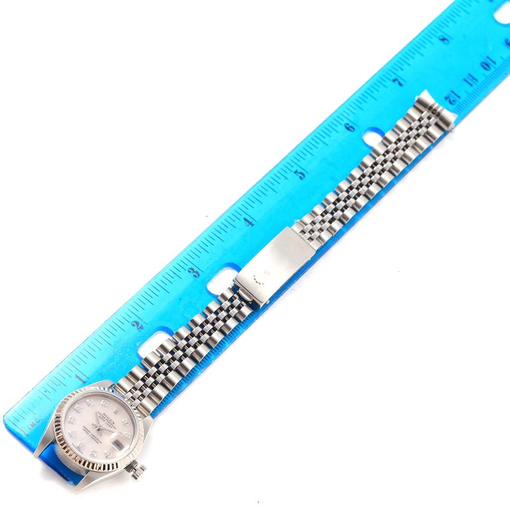 The Rolex Datejust 79174 Women
s Stainless Steel Mother of Pearl Dial 79174 Women
s Stainless Steel Mother of Pearl Dial watch is shown from above, highlighting the face, bezel, and bracelet, alongside a ruler for measurement.