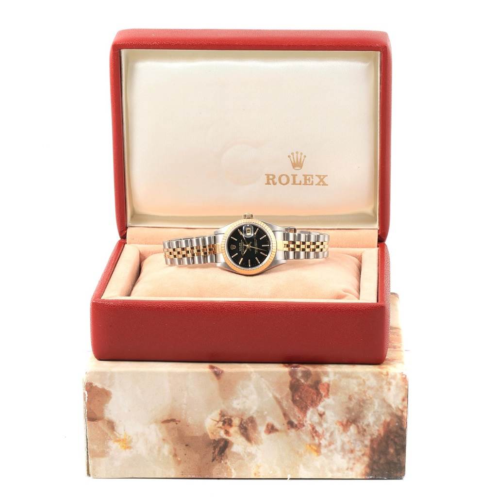 This image shows a Rolex Datejust 79173 Women
s Steel and Gold (two tone) Black Dial 79173 Women
s Steel and Gold (two tone) Black Dial watch, face forward, in its open red and beige box.