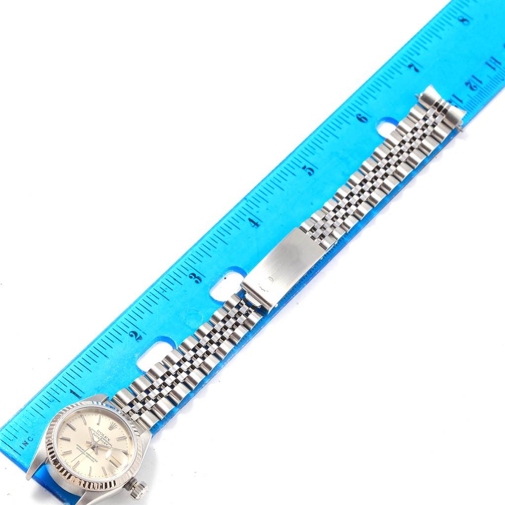 The Rolex Datejust 69174 Women's Stainless Steel Silver Dial 69174 Women's Stainless Steel Silver Dial watch is shown from the front, with its bracelet fully extended and aligned alongside a blue ruler.