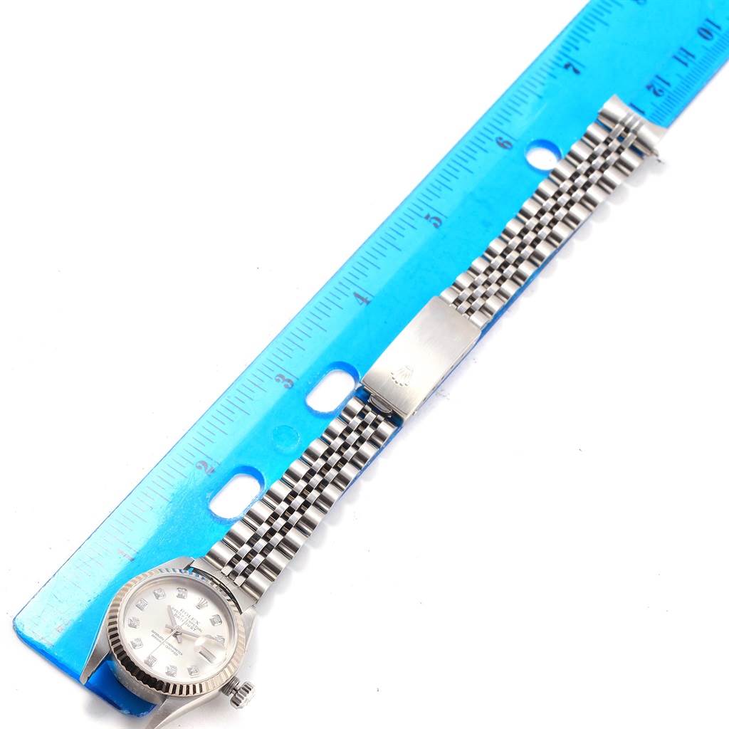 The Rolex Datejust 79174 Women's Stainless Steel Silver Dial 79174 Women's Stainless Steel Silver Dial watch is shown from the top, displaying the face and the full band alongside a blue ruler for measurement.