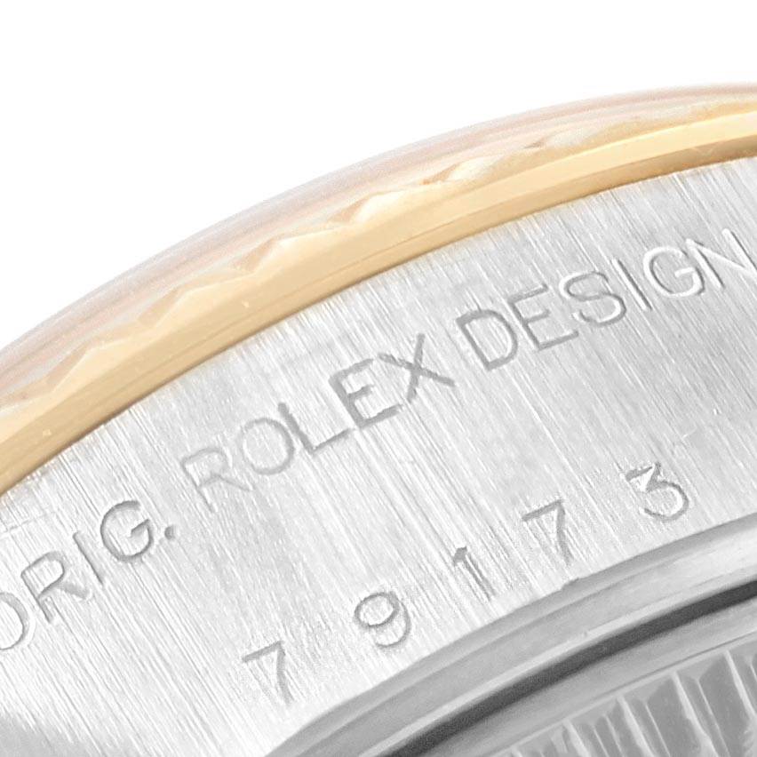 This close-up image shows a part of the bezel and the engraved text on the case back of a Rolex Datejust 79173 Women's Steel and Gold (two tone) Silver Dial 79173 Women's Steel and Gold (two tone) Silver Dial watch.