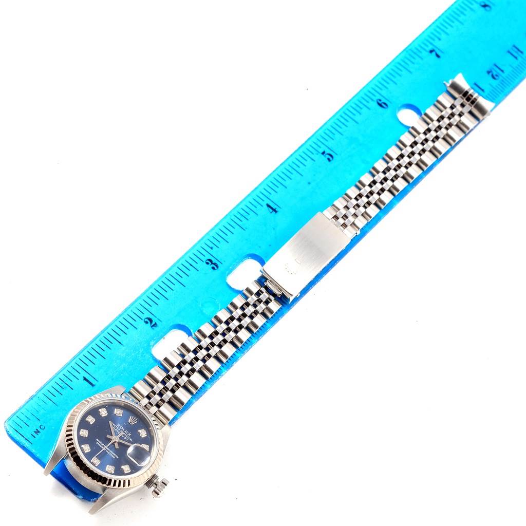 The image shows a Rolex Datejust 79174 Women's Stainless Steel Blue Dial 79174 Women's Stainless Steel Blue Dial watch laid flat next to a blue ruler, highlighting the bracelet's length.