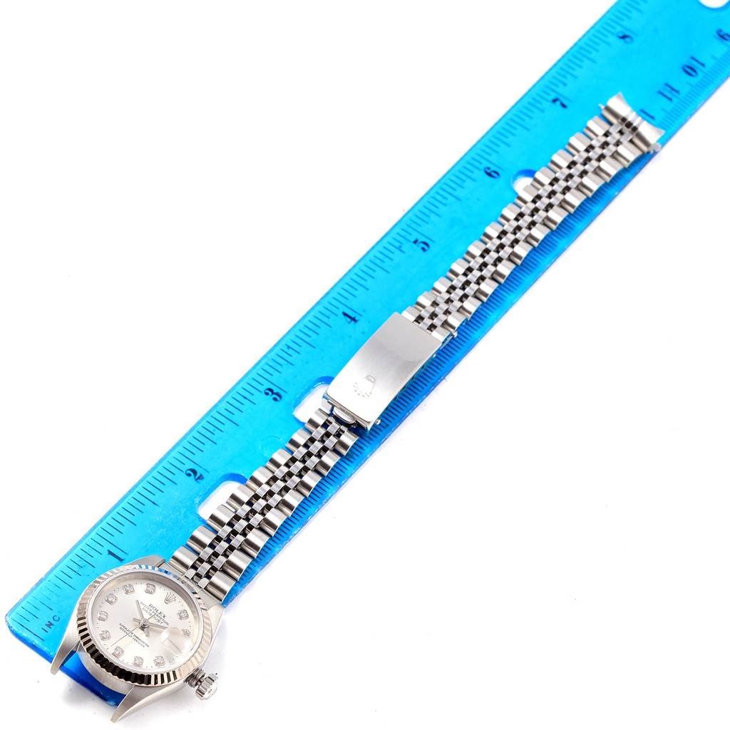 The image shows the Rolex Datejust 79174 Women
s Stainless Steel Silver Dial 79174 Women
s Stainless Steel Silver Dial watch from a top view, with the face, bracelet, and a clasp aligned next to a blue ruler.