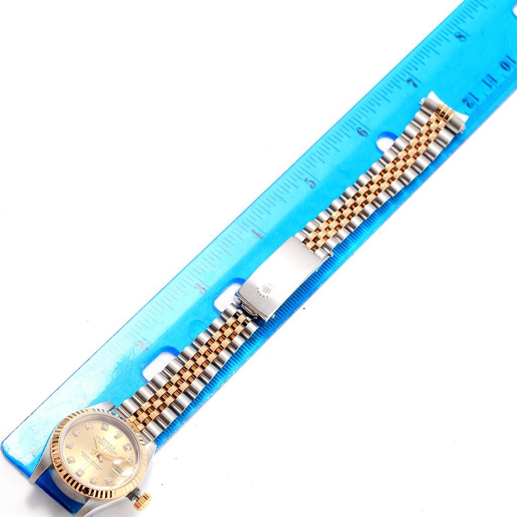 The image shows a Rolex Datejust 69173 Women
s Stainless Steel Champagne Dial 69173 Women
s Stainless Steel Champagne Dial watch with a two-tone Jubilee bracelet and clasp, aligned next to a blue ruler for size reference.