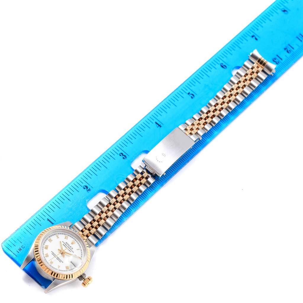 The image shows a Rolex Datejust 69173 Women
s Stainless Steel White Dial 69173 Women
s Stainless Steel White Dial watch laid flat next to a ruler, displaying its face, bezel, and bracelet.