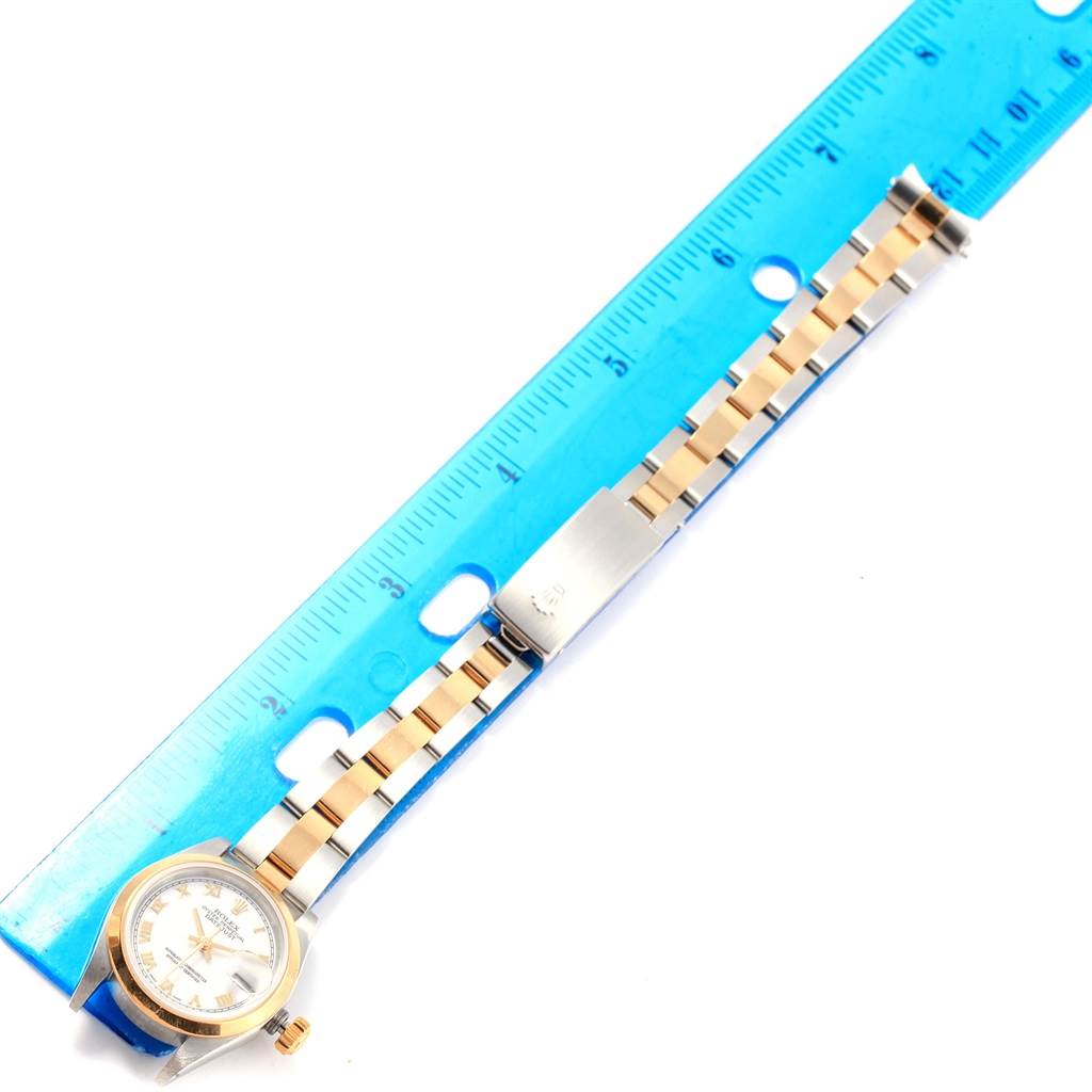 This image shows the Rolex Datejust 79163 Women's Steel and Gold (two tone) White Dial 79163 Women's Steel and Gold (two tone) White Dial watch face and bracelet next to a ruler from a top-down angle.