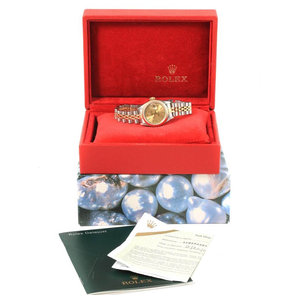 The Rolex Datejust 79173 Women's Steel and Gold (two tone) Champagne Dial 79173 Women's Steel and Gold (two tone) Champagne Dial watch is shown in its open red box, with booklets and certificates placed in front of the box.