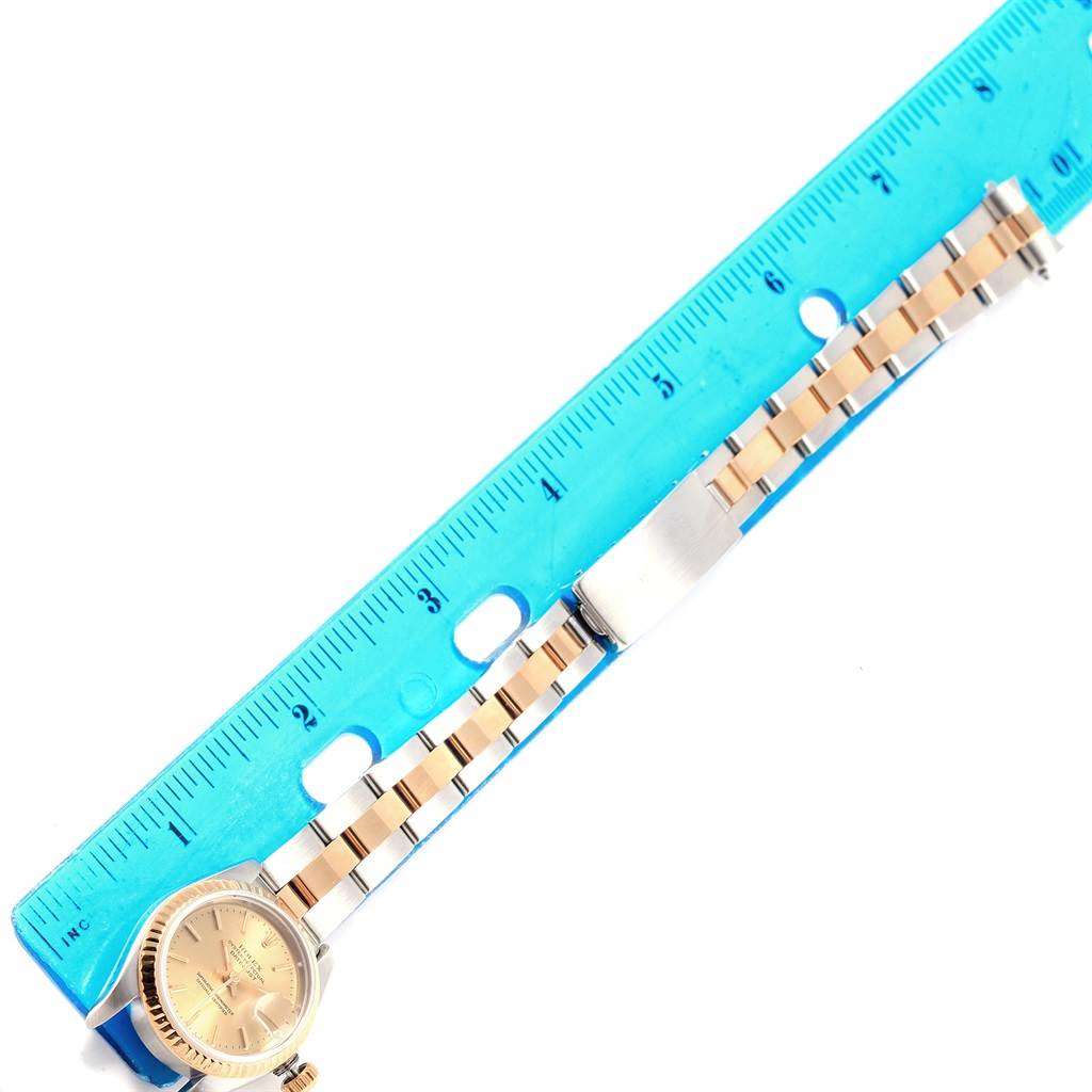 The image shows a Rolex Datejust 69173 Women
s Stainless Steel Champagne Dial 69173 Women
s Stainless Steel Champagne Dial watch laid flat next to a blue ruler, displaying its face and entire band.