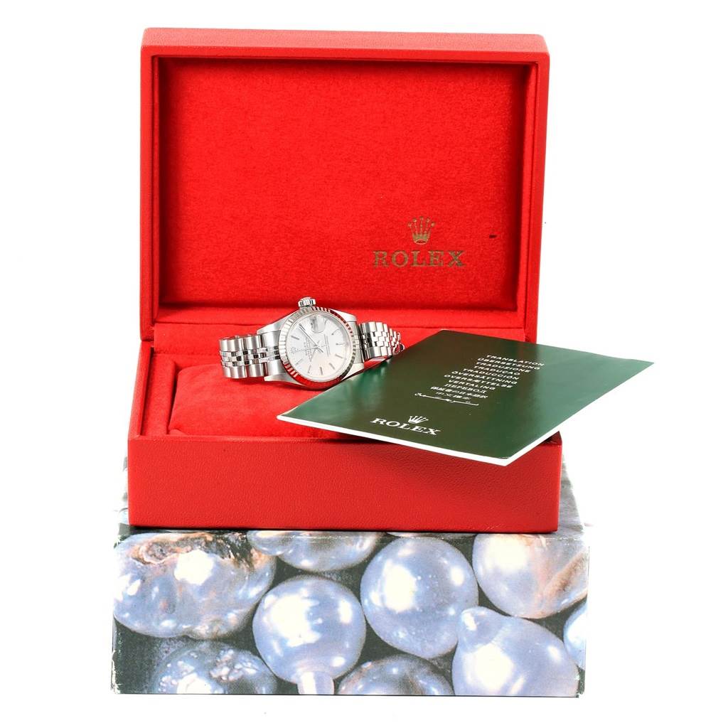 The Rolex Datejust 79174 Women
s Stainless Steel Silver Dial 79174 Women
s Stainless Steel Silver Dial watch is shown in an open red box, partially obscured by a green booklet.