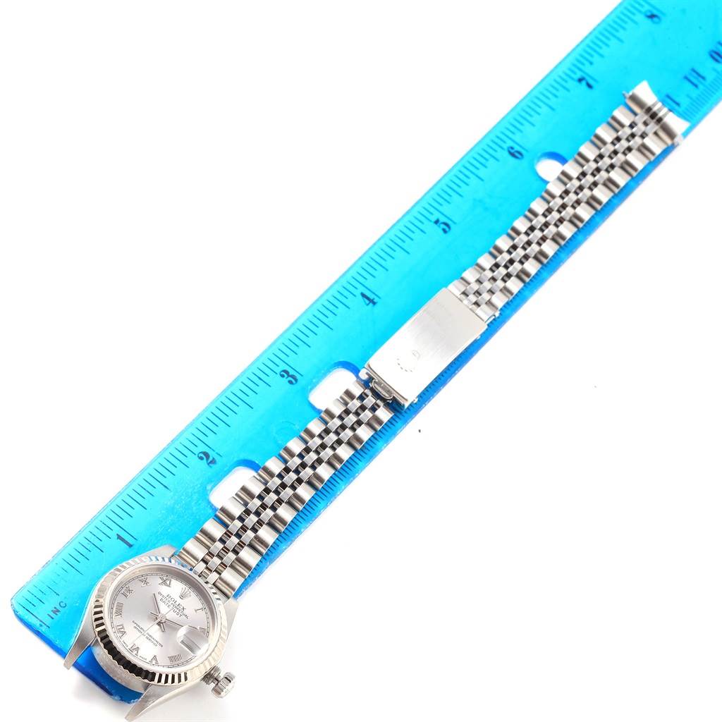 The image shows a top-down view of a Rolex Datejust 79174 Women
s Stainless Steel Silver Dial 79174 Women
s Stainless Steel Silver Dial watch with a full bracelet, placed next to a blue ruler.