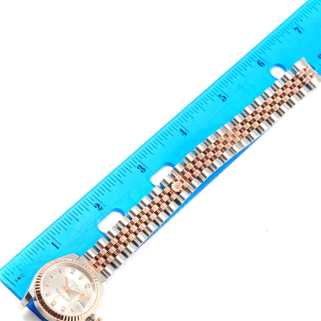 The photo shows a Rolex Datejust 179171 Women
s Steel and Gold (two tone) Silver Dial 179171 Women
s Steel and Gold (two tone) Silver Dial watch lying flat next to a blue ruler, with focus on the dial and bracelet.