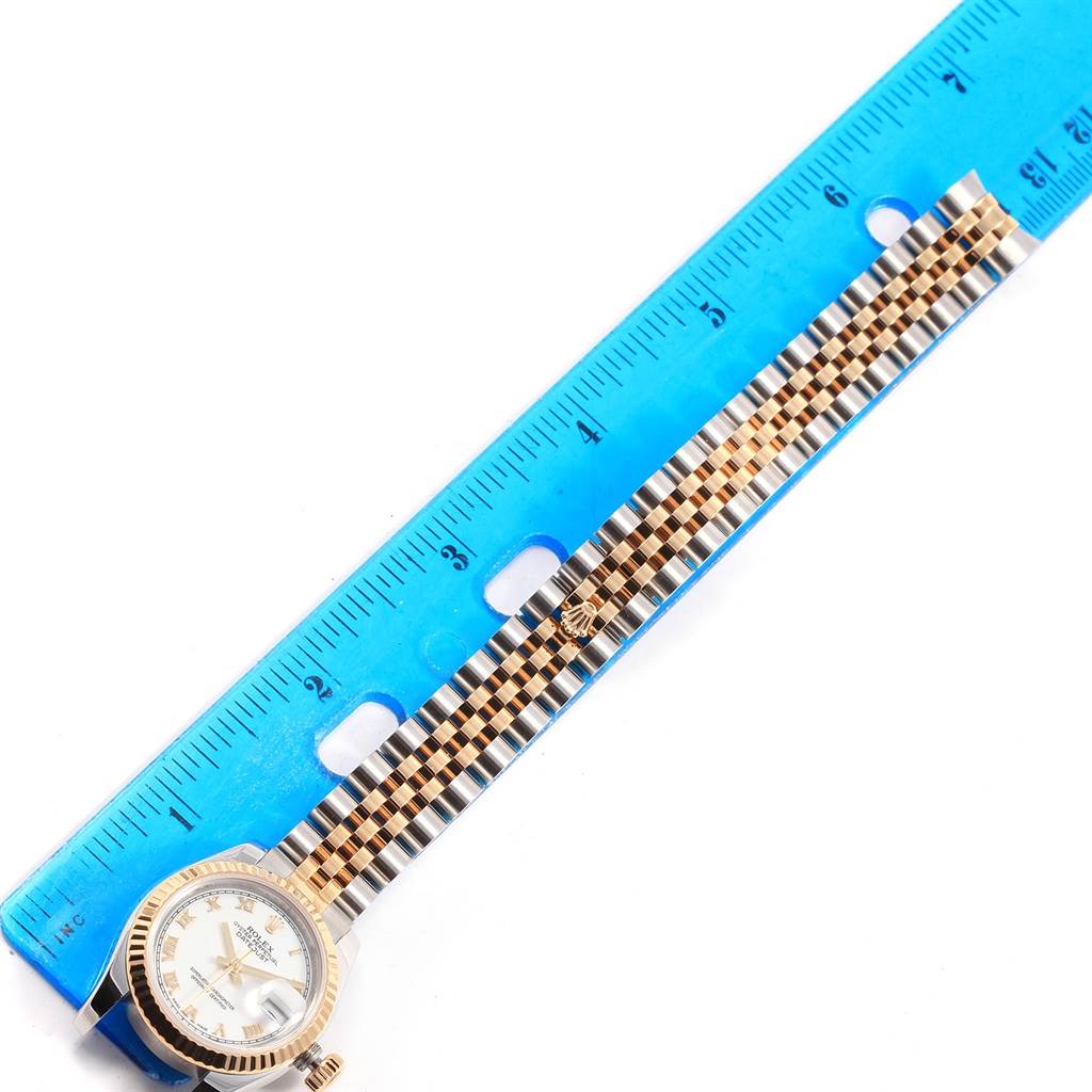 The Rolex Datejust 179173 Women's Steel and Gold (two tone) White Dial 179173 Women's Steel and Gold (two tone) White Dial watch is shown from a top view, displaying the dial, bezel, and metal bracelet alongside a blue ruler.