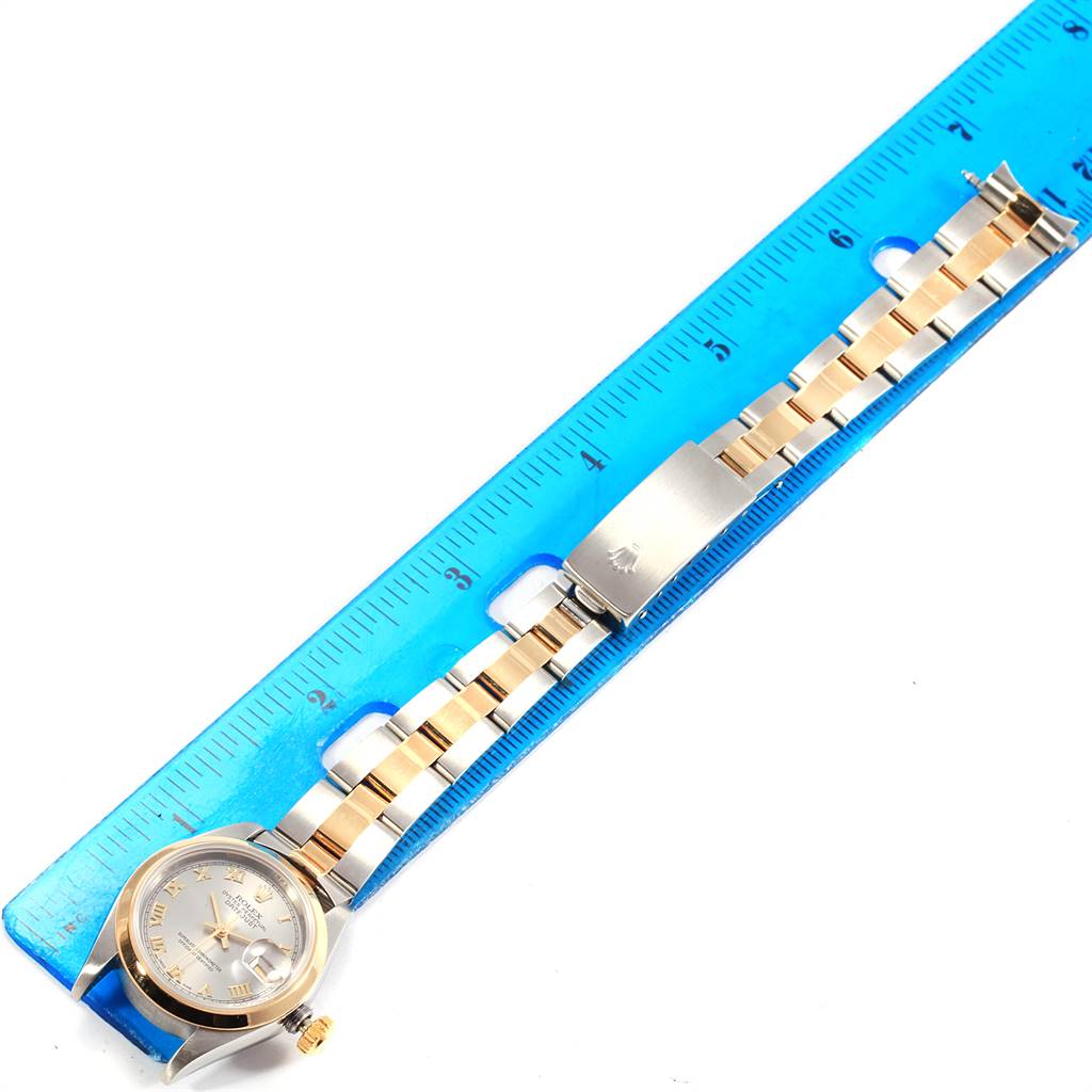 The image shows a Rolex Datejust 69163 Women's Steel and Gold (two tone) Grey Dial 69163 Women's Steel and Gold (two tone) Grey Dial watch and its band placed next to a blue ruler, viewed from above.