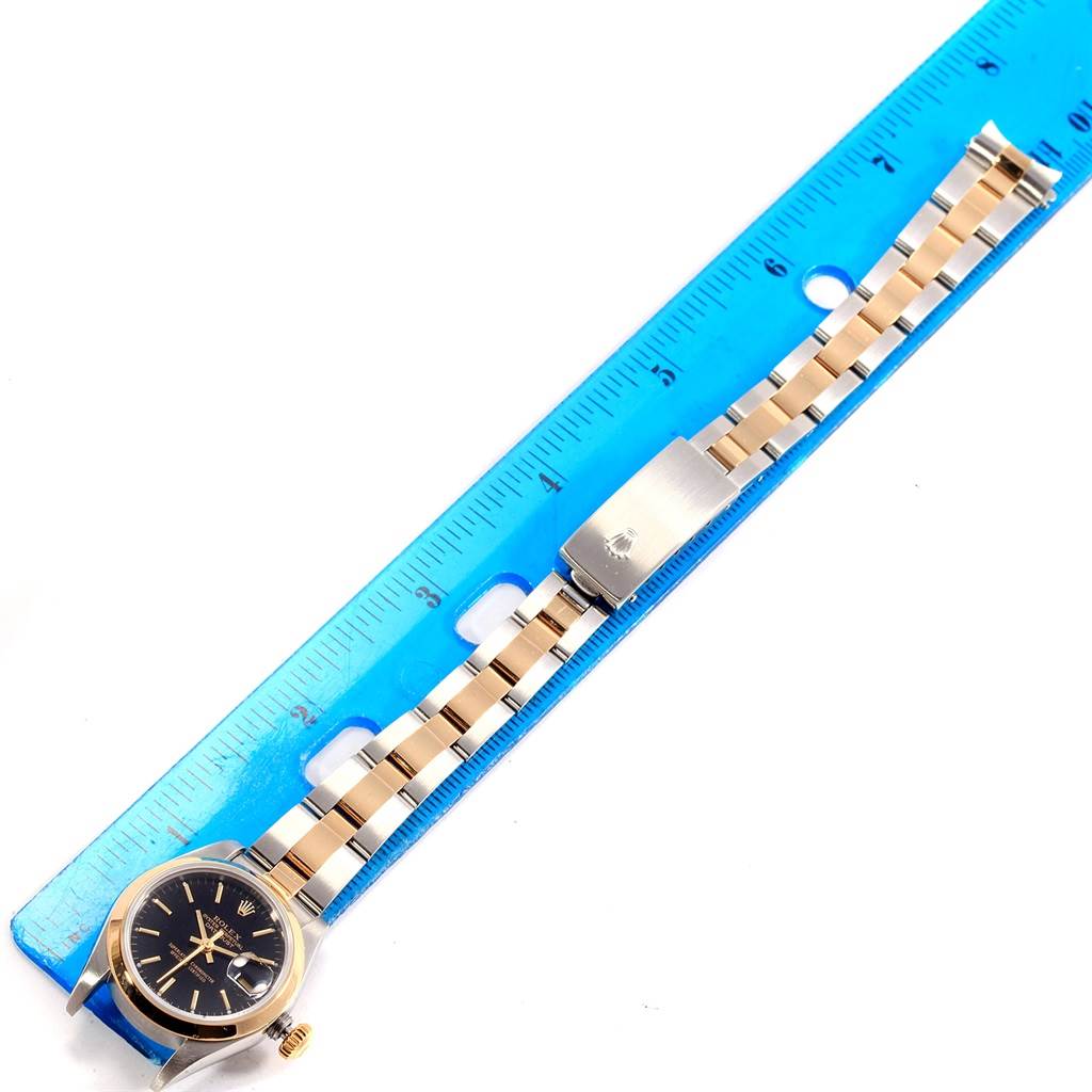 The image shows a Rolex Datejust 79163 Women's Steel and Gold (two tone) Black Dial 79163 Women's Steel and Gold (two tone) Black Dial watch with its full bracelet laid beside a ruler for scale, viewed from above.