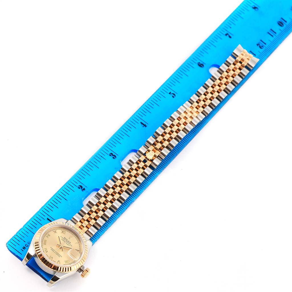 The image shows a Rolex Datejust 179173 Women's Steel and Gold (two tone) Champagne Dial 179173 Women's Steel and Gold (two tone) Champagne Dial watch laid flat next to a ruler, displaying the face and full bracelet.