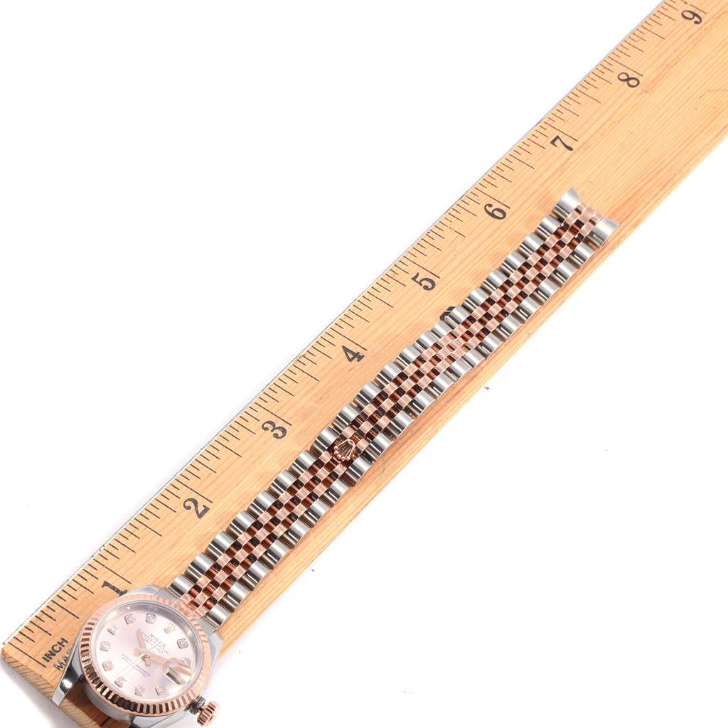 The Datejust Rolex watch is shown from a top-down angle, displaying the full watch and a portion of a ruler for scale.