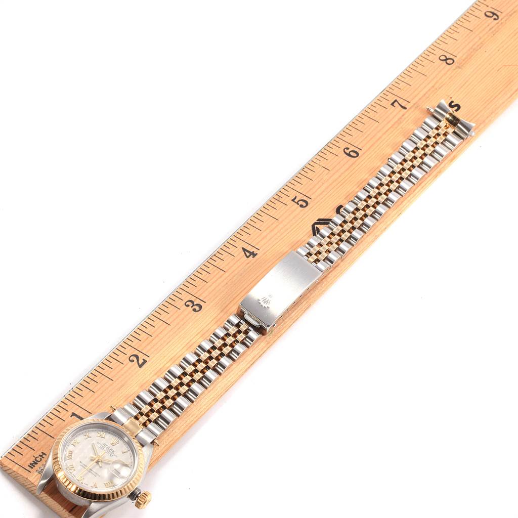 The Rolex Datejust 69173 Women
s Stainless Steel Beige Dial 69173 Women
s Stainless Steel Beige Dial watch is shown from a top-down angle with its face, bracelet, and clasp entirely visible alongside a ruler.