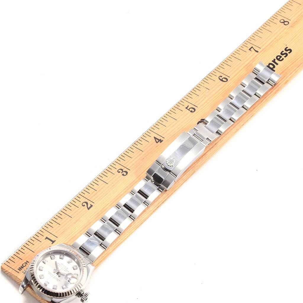 The image shows the Rolex Datejust 179174 Women
s Stainless Steel Silver Dial 179174 Women
s Stainless Steel Silver Dial watch laid out flat beside a ruler, displaying the band and face.