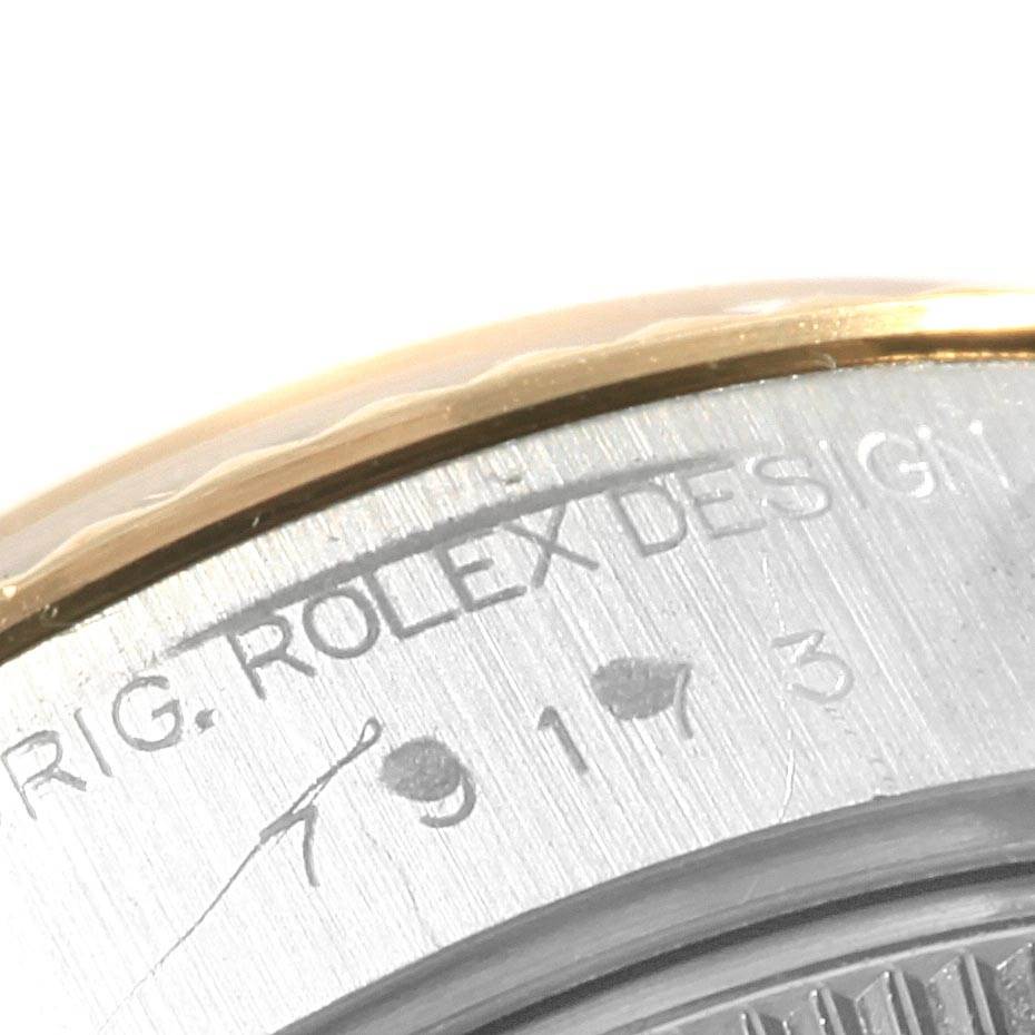 This image shows a close-up of the side of the case of a Rolex Datejust 79173 Women's Steel and Gold (two tone) Champagne Dial 79173 Women's Steel and Gold (two tone) Champagne Dial watch, featuring engraved text and part of the bezel.