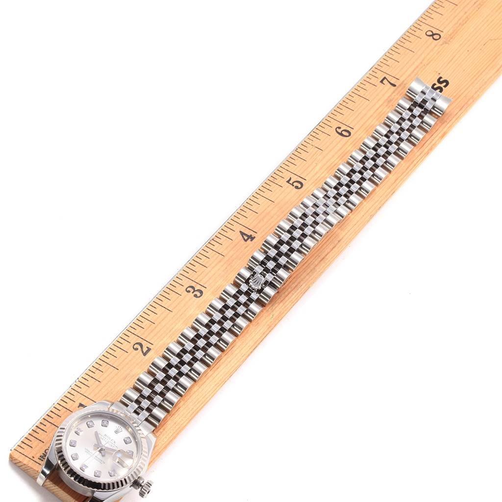 The Rolex Datejust 179174 Women
s Stainless Steel Silver Dial 179174 Women
s Stainless Steel Silver Dial watch is shown from the top, displaying its face and the full length of its metal bracelet alongside a ruler.