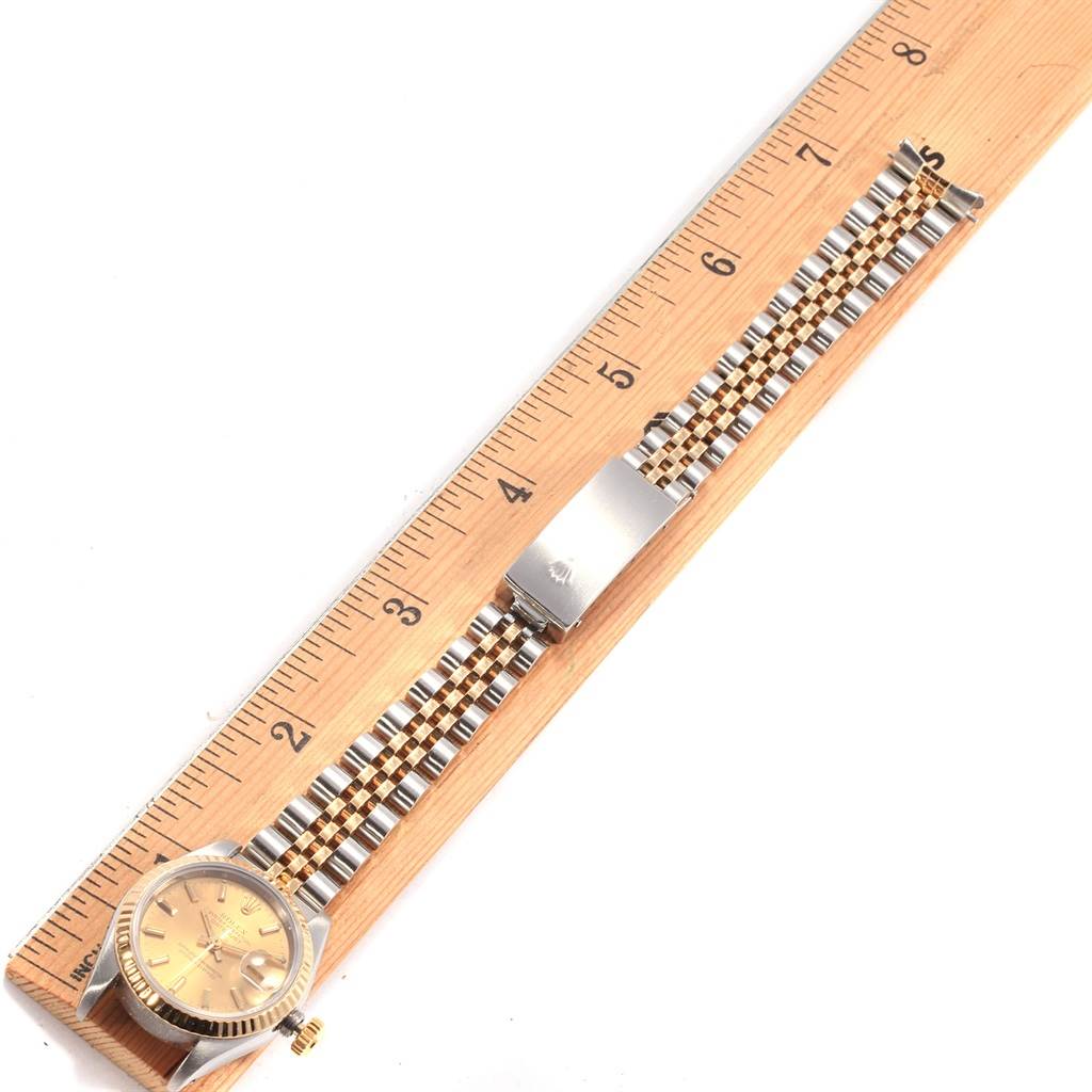 The Rolex Datejust 69173 Women's Stainless Steel Champagne Dial 69173 Women's Stainless Steel Champagne Dial watch is shown from a top view, displaying its dial, bracelet, and clasp, alongside a ruler for scale.