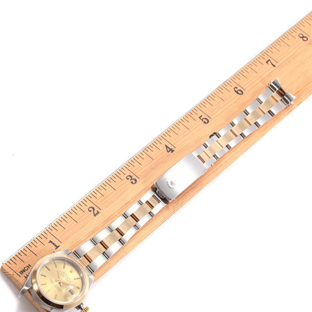 The Rolex Datejust 69163 Women's Stainless Steel Champagne Dial 69163 Women's Stainless Steel Champagne Dial watch is shown laid flat next to a ruler, highlighting its band and face.