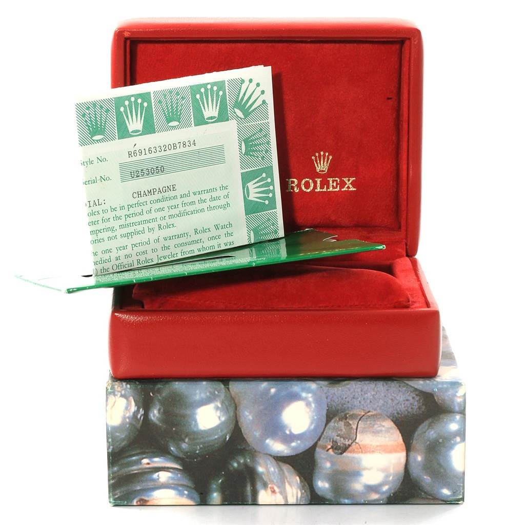 The image shows a red Rolex Datejust 69163 Women's Stainless Steel Champagne Dial 69163 Women's Stainless Steel Champagne Dial box with papers, including a certificate, placed inside and on top of the box.
