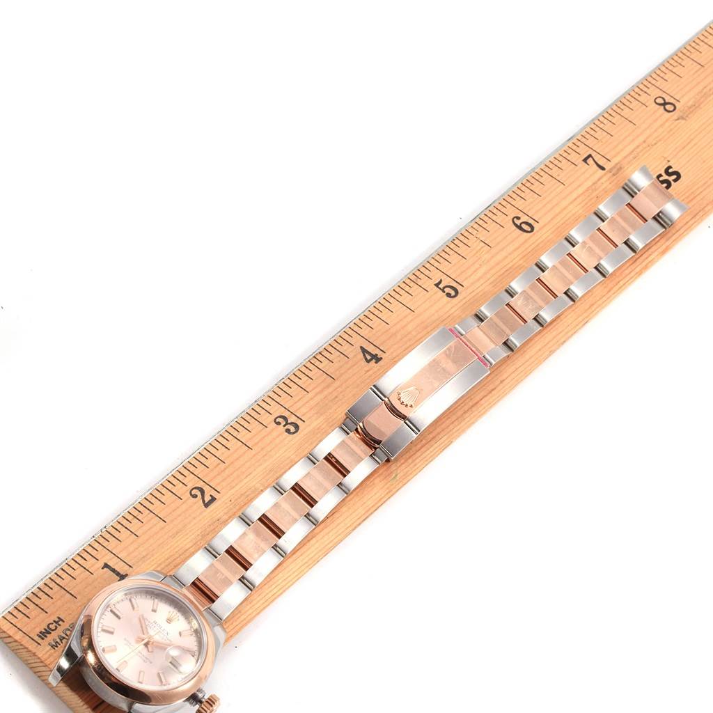 The image shows a Rolex Datejust 179161 Women's Steel and Gold (two tone) Pink Dial 179161 Women's Steel and Gold (two tone) Pink Dial watch placed alongside a ruler, displaying the watch's face and bracelet.