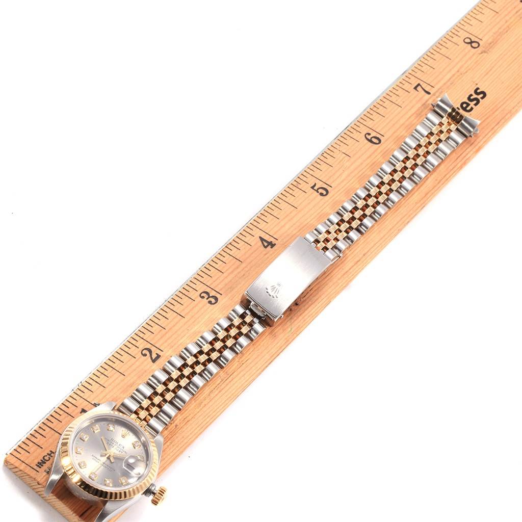 The Rolex Datejust 79173 Women's Steel and Gold (two tone) Grey Dial 79173 Women's Steel and Gold (two tone) Grey Dial watch is shown in a top-down view, displaying its face, bracelet, and clasp with a ruler beside it for scale.