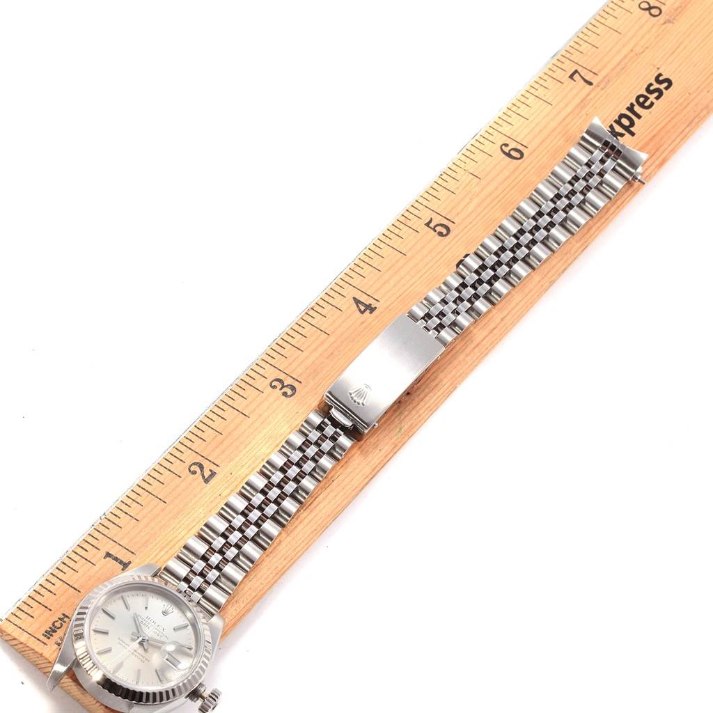 The Rolex Datejust 69174 Women's Stainless Steel Silver Dial 69174 Women's Stainless Steel Silver Dial watch is shown from a top-down angle, highlighting its face, bracelet, and clasp beside a ruler.