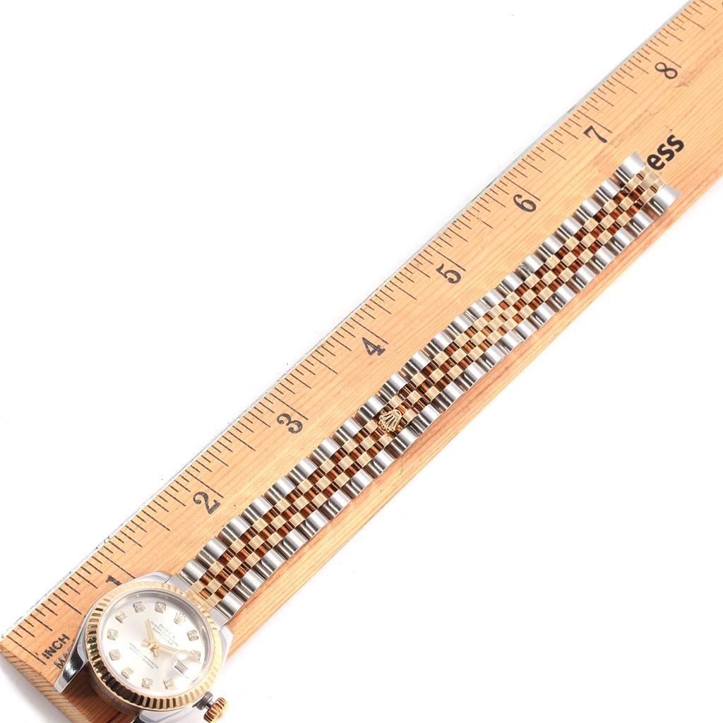 The Rolex Datejust 179173 Women's Steel and Gold (two tone) Silver Dial 179173 Women's Steel and Gold (two tone) Silver Dial watch is shown from an overhead angle, highlighting its dial, bezel, and bracelet against a ruler for scale.
