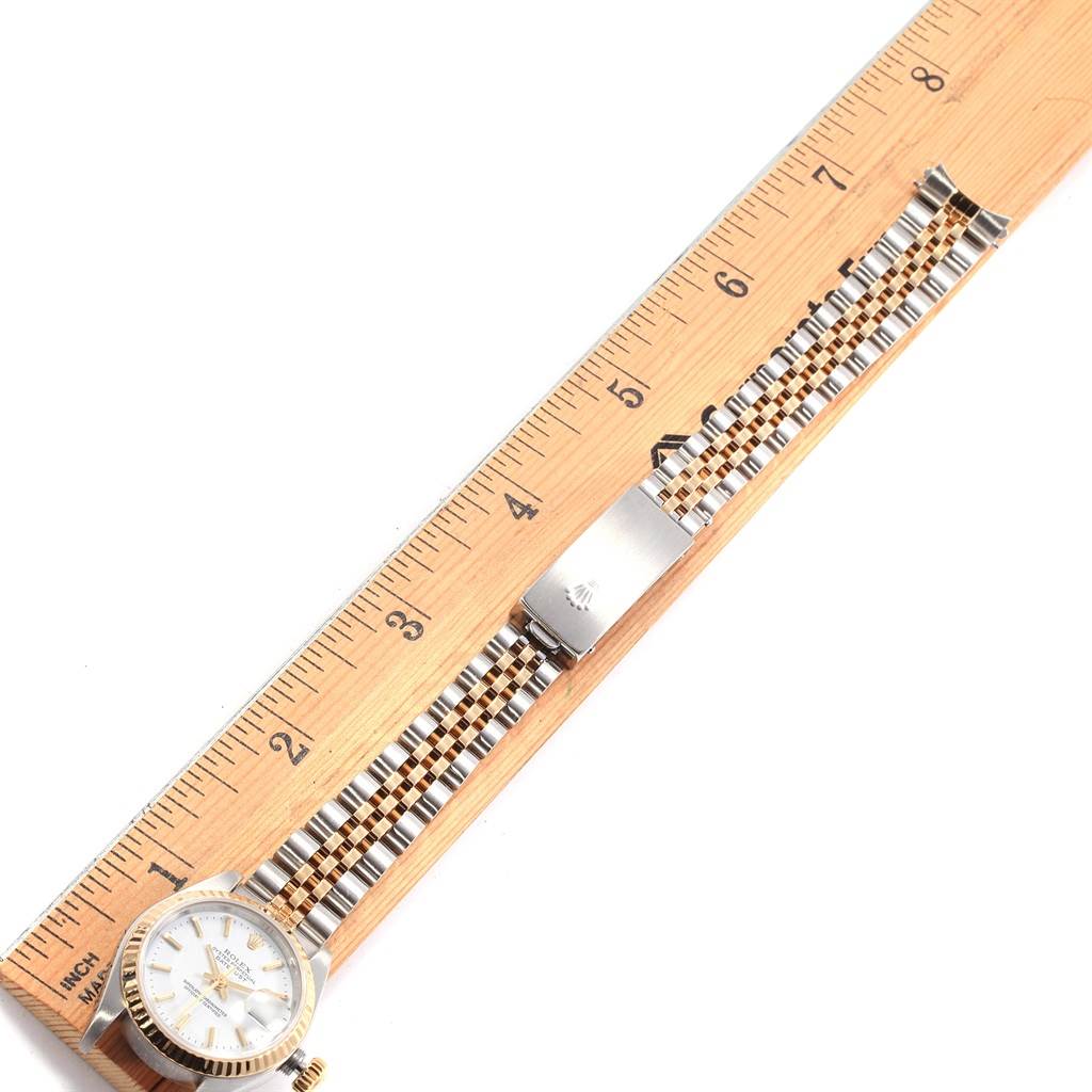 The image shows a Rolex Datejust 79173 Women's Steel and Gold (two tone) White Dial 79173 Women's Steel and Gold (two tone) White Dial watch laid flat next to a ruler, displaying its face, bracelet, and clasp.